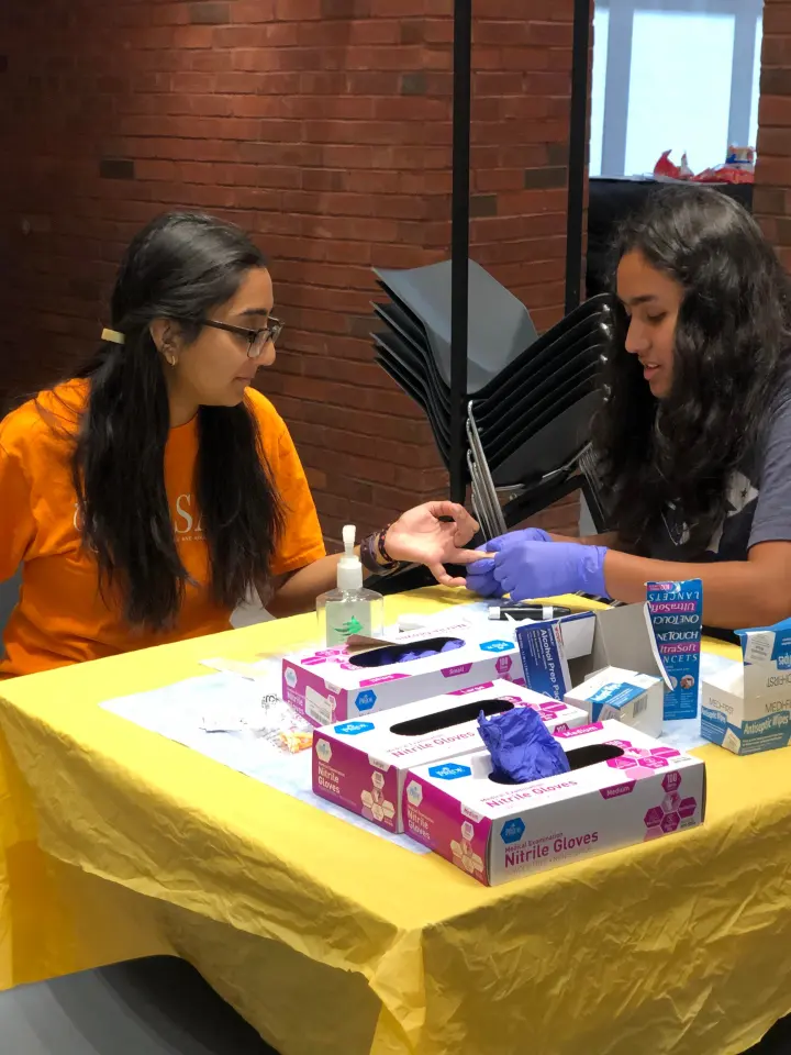 A Penn KDSAP volunteer assists another volunteer at a screening station